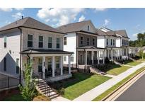 Street view of townhomes featuring brick and siding exteriors, well-manicured lawns, and inviting front porches at 167 Basil Street Dr, Cumming, GA 30040