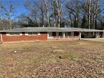 Single story brick home with small porch and carport surrounded by trees at 6756 Brookwood Cir, Jonesboro, GA 30043