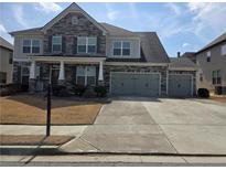 Beautiful two-story home with stone accents, a well-maintained lawn, and a three-car garage on a sunny day at 1200 Bar Harbor Pl, Lawrenceville, GA 30044