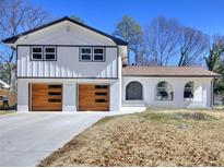 Charming two-story home features a modern white brick and siding exterior, wood garage doors and inviting arched porch at 406 Jordan Dr, Tucker, GA 30084