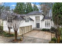 Stunning white facade with a three-car garage and a double-door entrance framed by two-story windows at 4000 Wieuca Rd Ne, Atlanta, GA 30342