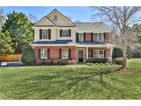 Charming two-story home with a brick facade, manicured lawn, and mature trees, exuding classic elegance and curb appeal at 705 Chanson Sw Dr, Marietta, GA 30064