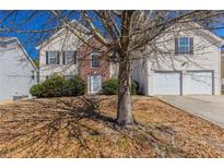 Traditional two-story home with a brick facade, mature landscaping, and a two-car garage at 7635 Jumpers Trl, Fairburn, GA 30213