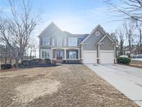 Charming two-story home with a well-manicured lawn, a two-car garage, and a welcoming front porch at 3348 Terrace Hedge Pl, Dacula, GA 30019