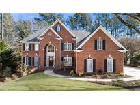 Traditional brick home with manicured lawn, arched entryway, and black shutters at 3040 Greatwood Xing, Alpharetta, GA 30005