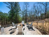 Inviting backyard fire pit area with stamped concrete patio and seating surrounded by a wooded landscape at 139 Stargaze Rdg, Canton, GA 30114