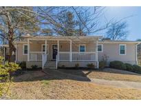 Charming single-story home featuring a covered front porch, a well-manicured lawn, and professional landscaping at 5498 Balmoral Dr, Douglasville, GA 30135