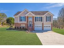 Charming two-story home featuring a brick facade, two-car garage, and well-manicured lawn at 4125 Mark Todd Ct, Hoschton, GA 30548