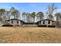 Unique home with stone accents, modern windows, and mature trees offering both character and natural surroundings at 2533 Schooner Cv, Snellville, GA 30078