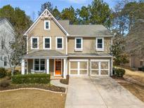 Charming two-story home boasts a well-manicured lawn and a welcoming front porch with an inviting orange front door at 313 Revolution Dr, Peachtree City, GA 30269