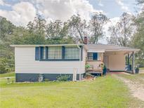 Charming single-story home featuring a cozy front porch, carport, and well-maintained lawn at 1202 Coan Dr, Locust Grove, GA 30248