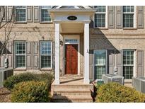 A welcoming brick home featuring a charming entrance with a covered porch and shuttered windows at 146 Rowan Ave, Alpharetta, GA 30009