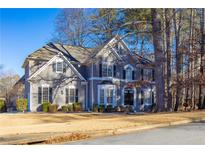 Charming two-story home with a well-manicured front yard and classic architectural details under a clear blue sky at 251 Waterford Cove Dr, Suwanee, GA 30024