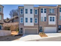 New townhouse showcases a two-car garage and brick facade, complemented by a lush, landscaped setting at 399 Skylar Se Way, Atlanta, GA 30315