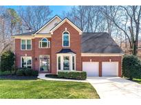 Charming two-story brick home with manicured lawn, two-car garage, and mature landscaping at 565 Ashvale Overlook, Alpharetta, GA 30005