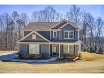 Charming two-story home features stone accents, a covered front porch, and professionally landscaped yard at 50 Crabapple Ridge Dr, Oxford, GA 30054