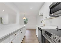 Bright kitchen features white cabinetry, stainless steel appliances, stone countertops, and gold hardware at 2396 Lawrenceville Hwy # V, Decatur, GA 30033