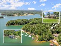 Stunning aerial view of a lakeside property featuring a home, docks, and lush greenery at 7565 Heard Rd, Cumming, GA 30041