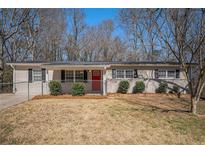 Charming single-story home featuring a well-maintained lawn and a vibrant red front door at 542 Oak Hills Sw Rd, Mableton, GA 30126