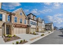 Beautiful townhome exterior featuring brick, stone, attached garages, and manicured landscaping at 116 Via Roma, Woodstock, GA 30188
