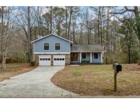 Charming blue two-story home featuring a stone-accented garage and inviting front porch at 9635 Loblolly Ln, Roswell, GA 30075