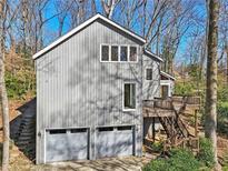 Charming gray home with a two-car garage and a wooden deck surrounded by lush trees at 566 Hickory Hills Ct, Stone Mountain, GA 30083