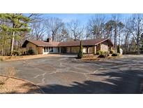 Spacious ranch-style home featuring a porte-cochere, stone accents, mature trees, and a wide driveway at 2499 E Maddox Rd, Buford, GA 30519