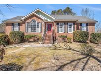 Charming brick home with manicured shrubs, steps up to a red front door, and classic architectural details at 2101 Oakleaf Ln, Lithia Springs, GA 30122