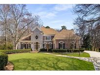Imposing two-story brick home with manicured lawn and mature trees exuding curb appeal and classic charm at 715 Newport Holw, Alpharetta, GA 30005