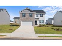 Charming two-story home features brick and siding, a two-car garage, and a well-manicured lawn at 165 Aster Avenue, Locust Grove, GA 30248