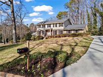 Charming two-story home featuring traditional architecture and a well-manicured front lawn with mature trees at 7675 Ryefield Dr, Sandy Springs, GA 30350