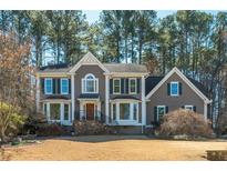 Charming two-story home with stone accents, a manicured lawn and mature trees at 11120 Surrey Park Trail, Johns Creek, GA 30097