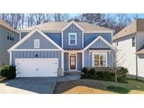 Charming two-story home features a blue exterior, landscaped yard, and a two-car garage, creating curb appeal at 147 Treeline Trl, Canton, GA 30115