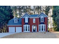 Charming red brick two-story home with manicured lawn and attached two car garage at 3075 Elizabeth Ln, Snellville, GA 30078