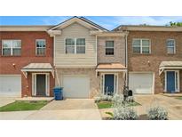 Charming townhome featuring brick facade, attached garage, and welcoming front entryway with landscaped garden at 5019 Lower Elm St, Atlanta, GA 30349