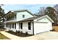 Two-story home features a white brick and light green exterior, black trim, a balcony and attached garage at 356 Greenwood Nw Dr, Lilburn, GA 30047