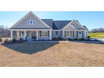 Charming single-story home featuring a covered front porch, stone accents, and manicured lawn at 5410 Crow Dr, Cumming, GA 30041