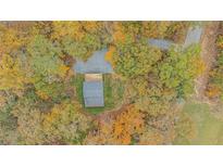 Aerial view of a secluded home nestled among colorful fall foliage and a gravel driveway at 115 Bruce Rd, Douglasville, GA 30134