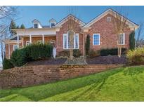 Charming brick home with dormers and covered porch, set on a beautifully landscaped lawn with retaining wall at 2850 Brandy Ln, Cumming, GA 30041