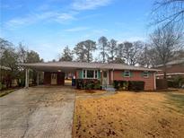 Charming brick home with a covered carport and landscaped front yard under a blue sky at 728 Birchwood Sw Ln, Marietta, GA 30060