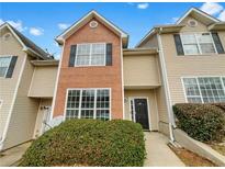 Inviting townhouse with a mix of brick and vinyl siding, featuring large windows and well-maintained landscaping at 1485 Riverrock Trl, Riverdale, GA 30296
