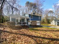 Inviting two-story home featuring a cozy front porch and attached garage, nestled amongst mature trees at 5407 Effingham Ct, Lithonia, GA 30038