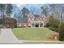 Traditional two-story brick home featuring a charming front porch and lush lawn at 4000 Rockingham Dr, Roswell, GA 30075