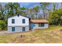 Charming split-level home with blue door and gray brick, nestled among mature trees and a yard at 6684 Heathrow Ln, Stone Mountain, GA 30087