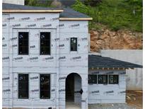 Unfinished two story exterior showing Typar wrap, black window frames and arched door frame detail at 10849 Serenbe Ln, Chattahoochee Hills, GA 30268