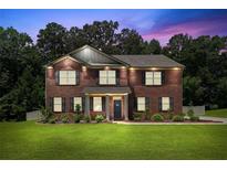 Beautiful brick two-story home with manicured lawn and inviting curb appeal at dusk at 1326 Harlequin Way, Stockbridge, GA 30281