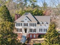 Elegant two-story home featuring black shutters, a brick foundation, and a welcoming front porch with staircase at 4399 Jett Nw Pl, Atlanta, GA 30327