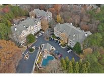 Beautiful aerial view of condo community surrounded by mature trees and featuring a pool and parking at 115 Ashford Cir, Dunwoody, GA 30338