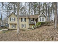 Charming split-level home featuring a welcoming front porch and classic black shutters surrounded by mature trees at 830 White Stag Ln, Canton, GA 30115