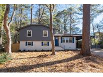 Charming home featuring a split-level design, gray and white exterior, blue shutters, and a well-maintained front yard at 8744 Bellwood Ct, Riverdale, GA 30274